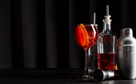 Коктейль с апельсином, шейкер и бутылка на тёмном фоне